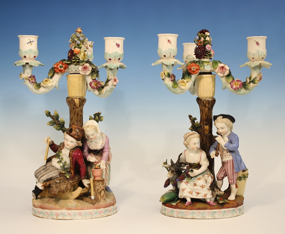 A pair of Sitzendorf candelabra one depicting a musician playing a recorder to a female seated upon