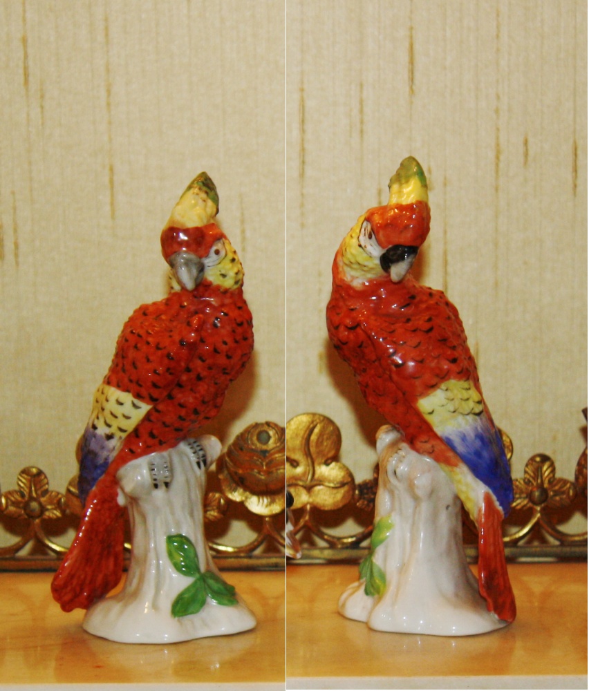 A pair of Continental porcelain models of parrots on leafy branches, marked with spurious gold