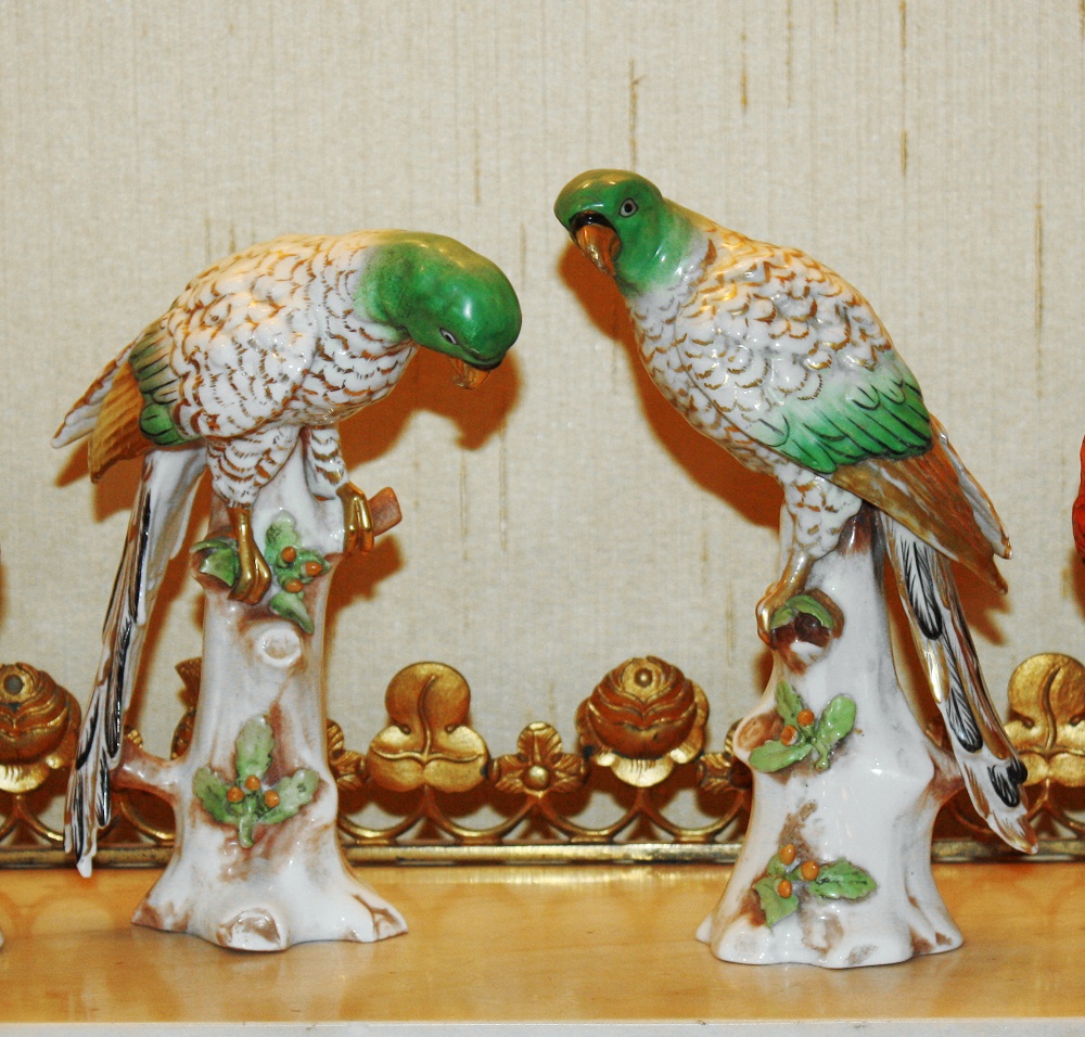 A pair of Continental porcelain models of parrots on branches with spurious Chelsea style gold