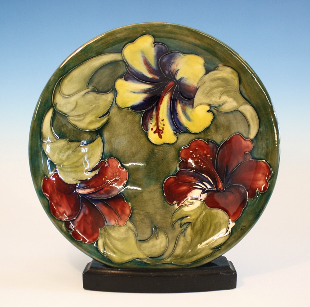 A Moorcroft shallow dish 1960s, circular form with shallow foot, in the hibiscus pattern on a green