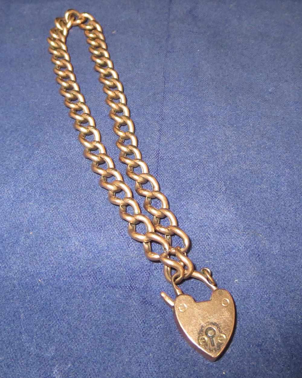 A yellow metal chain bracelet (unmarked) with a 9 carat hallmarked gold heart lock