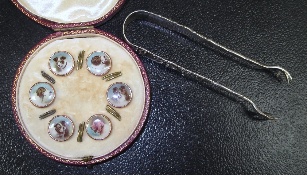 A set of 6 gilt mounted celluloid dog buttons, red Morocco case; a pair of silver sugar tongs