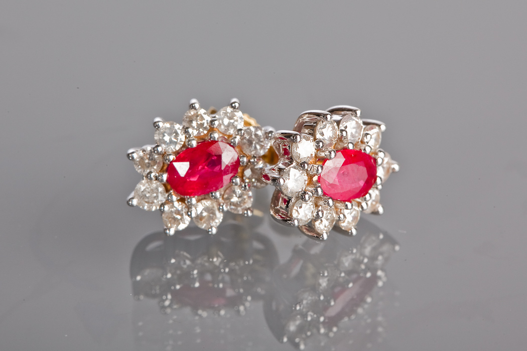 PAIR OF RUBY AND DIAMOND CLUSTER EARRINGS each set with a central oval ruby surrounded by brilliant