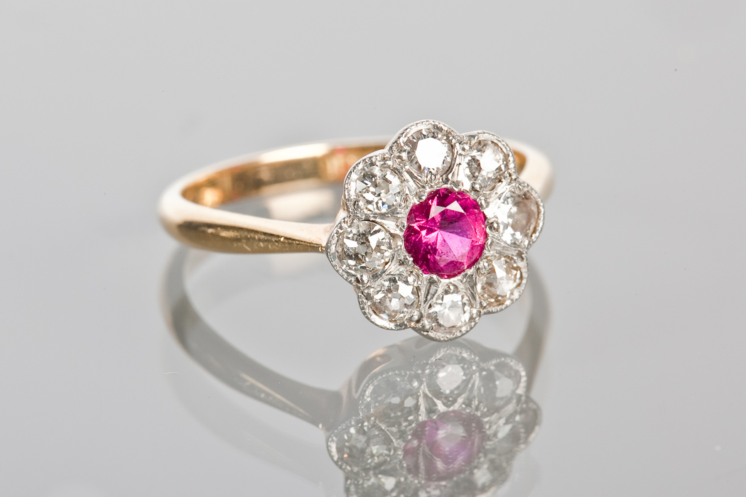 EARLY TWENTIETH CENTURY RUBY AND DIAMOND CLUSTER RING the central brilliant cut ruby approximately