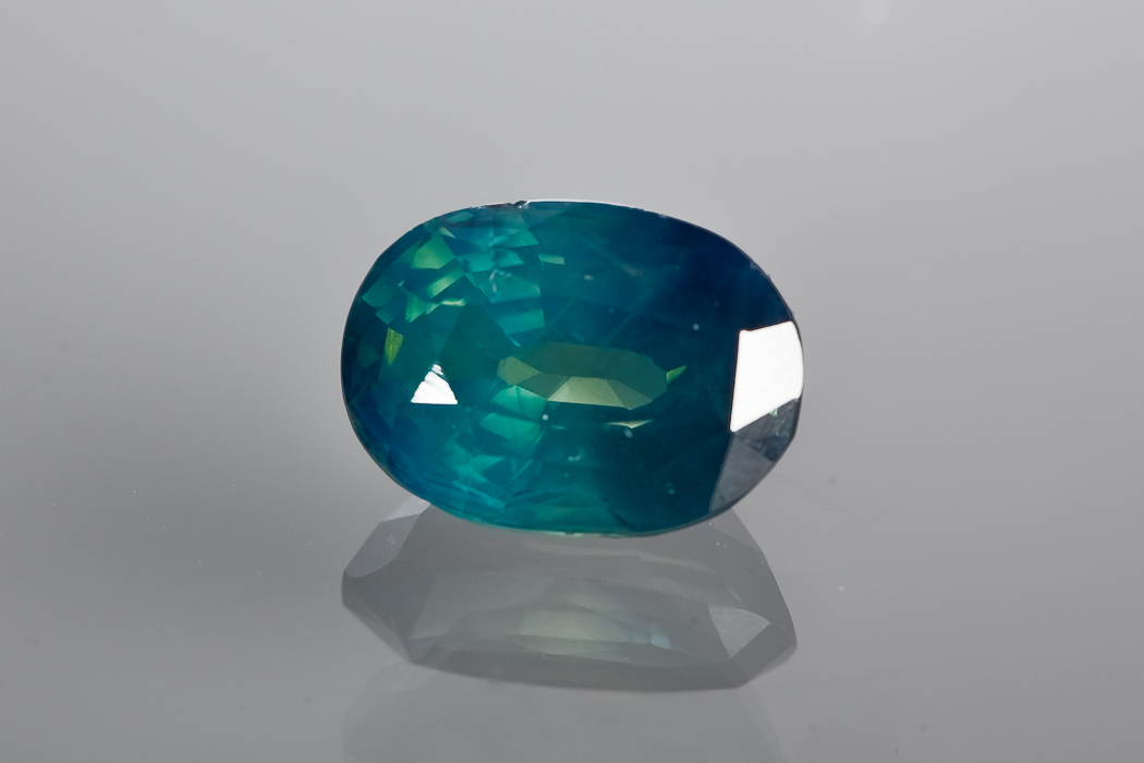 CERTIFICATED UNMOUNTED BLUE-GREEN SAPPHIRE oval mixed cut, 5.19 carats, with an IGI certificate