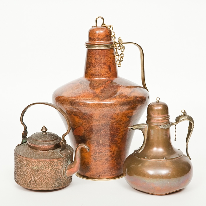 TWO EASTERN TEAPOTS AND A LARGE WATER CARRIER the teapots in copper, one with swing handle and one