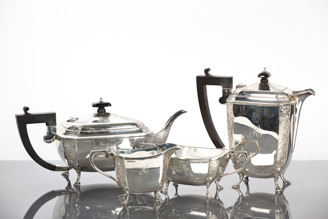 SILVER FOUR PIECE TEA SERVICE of square form with canted foliate engraved corners, raised on square