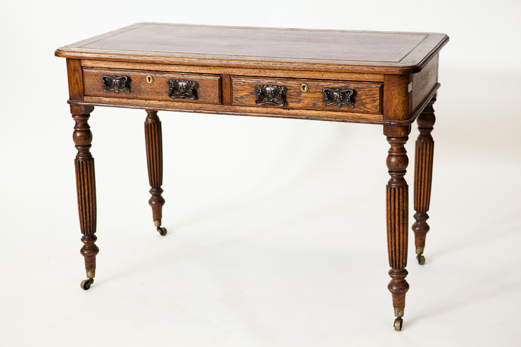 LATE VICTORIAN OAK WRITING TABLE with red leather skiver, on fluted legs and brass casters, 75cm