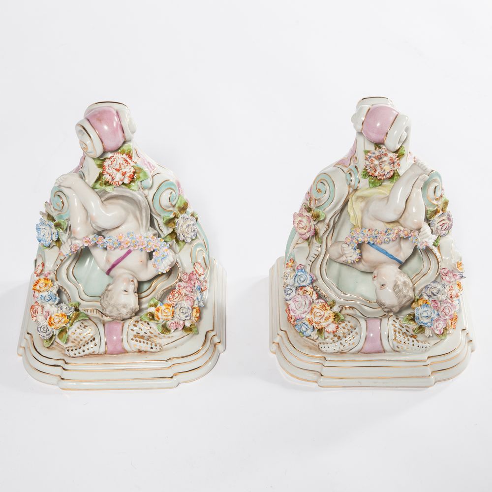 A PAIR OF GERMAN PORCELAIN AND FLOWER ENCRUSTED WALL BRACKETS, 
each modelled with a seated cherub