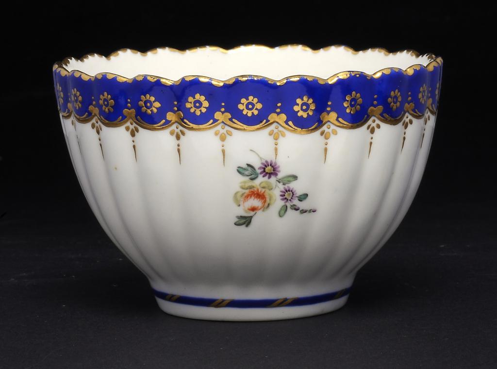 A DERBY REEDED TEA BOWL  painted with flowers beneath blue and gilt border,   gold anchor and D,