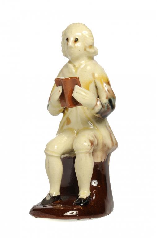 AN ASTBURY TYPE CREAMWARE FIGURE OF A SEATED MAN   with underglaze oxide decoration, the base of