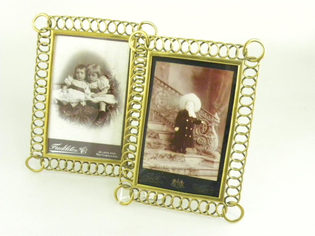 A PAIR OF EDWARDIAN LACQUERED BRASS PHOTOGRAPH FRAMES WITH LOOP SURROUND AND A RING AT EACH CORNER