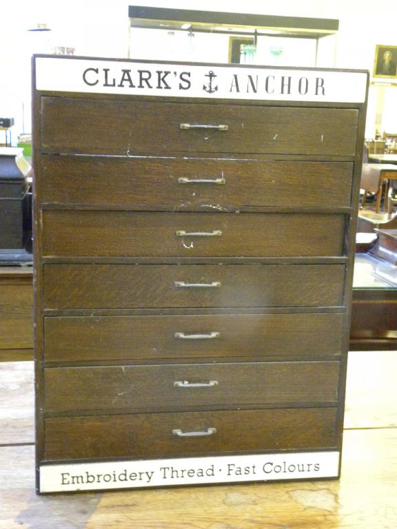 A CLARK`S EMBROIDERY THREAD CABINET IN STAINED OAK FITTED SEVEN GLASS FRONTED DRAWERS, C1930S