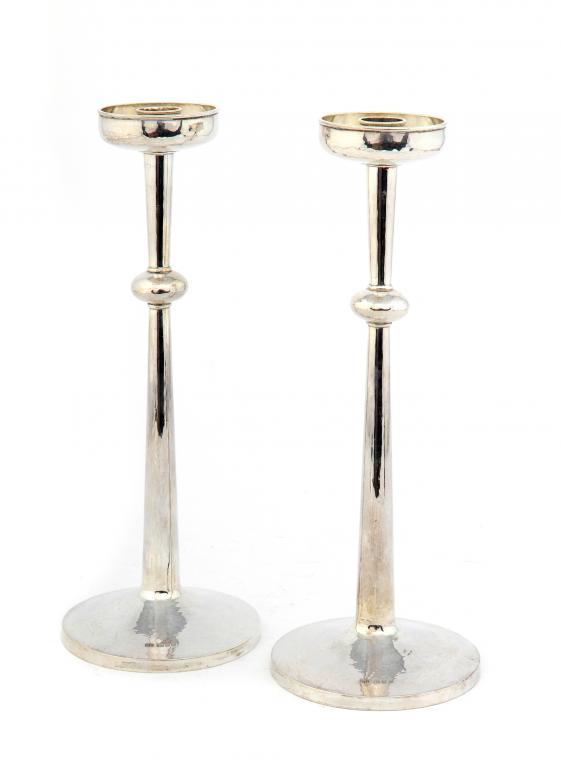 A PAIR OF GUILD OF HANDICRAFT SILVER CANDLESTICKS with lightly hammer textured drip pan and foot,