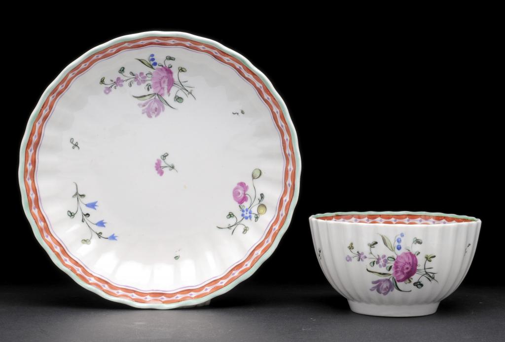 AN EARLY NEW HALL FLUTED TEA BOWL AND SAUCER enamelled with pattern No 3 of flower sprays and sprigs