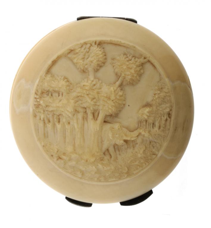 A CONTINENTAL IVORY COMPACT  the round lid and underside carved with an elephant or tropical