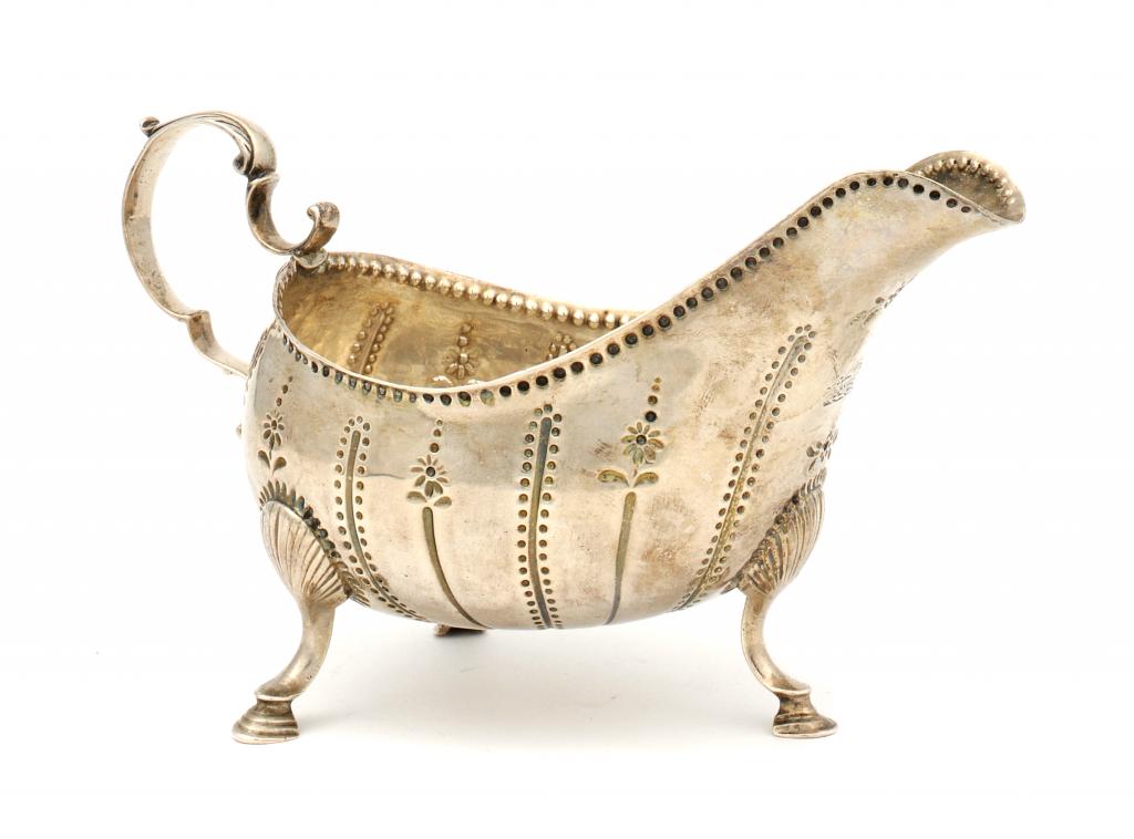 AN IRISH GEORGE III SAUCE BOAT  with punched and fluted decoration,  on three hoof feet, crested,