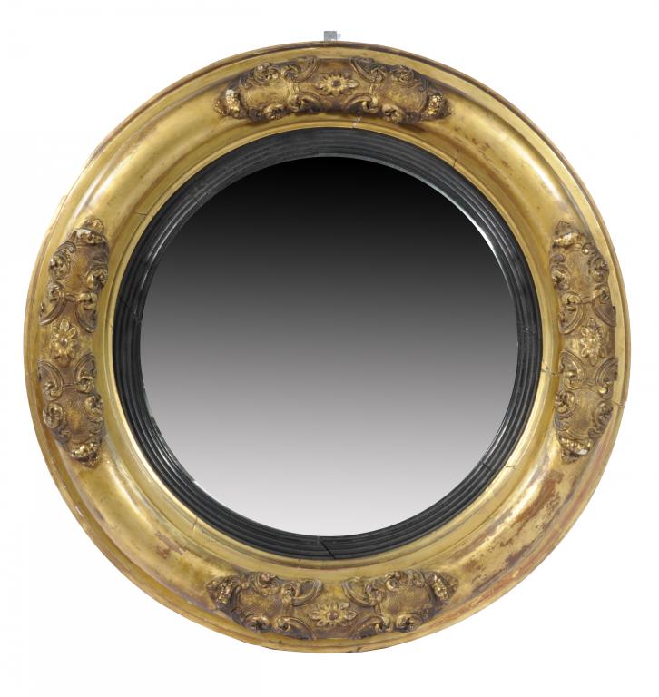 A GEORGE IV GILTWOOD MIRROR the convex plate in reeded, ebonised slip, the frame clasped in four