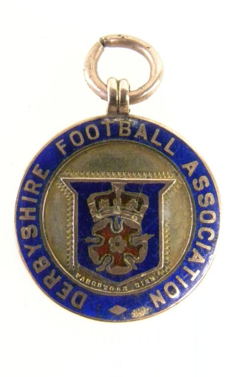 A 9CT GOLD AND ENAMEL DERBYSHIRE FOOTBALL ASSOCIATION PRIZE WATCH FOB MEDAL, REVERSE EMBOSSED MEDAL