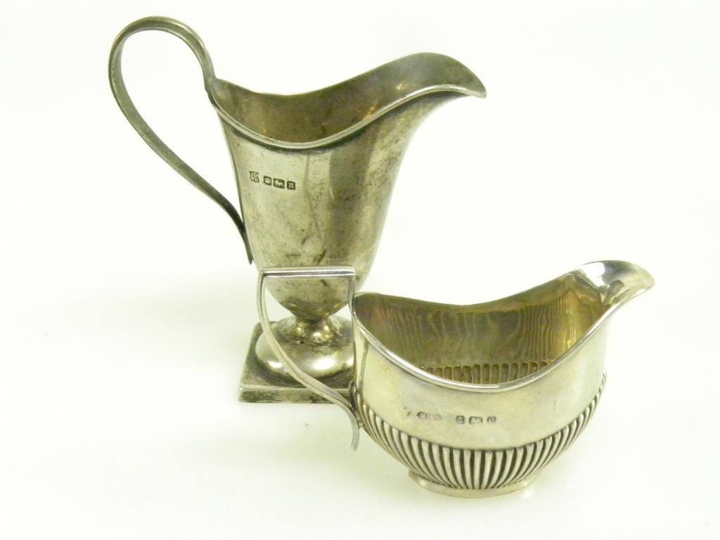 AN EDWARD VII SILVER CREAM JUG OF HELMET SHAPE, SHEFFIELD 1905, AND A SMALLER OVAL SILVER CREAM JUG,