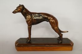 A brass model of a greyhound on wooden plinth base