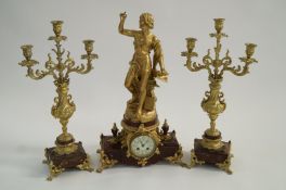 Garniture trio of gilt ormolu candelabra and ornate figural mantle clock; with key and pendulum -