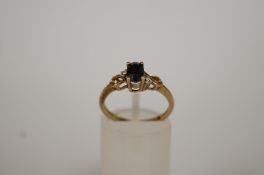 A sapphire and diamond 9ct gold ring, the oval cut flanked by single cuts, finger size L 1/2