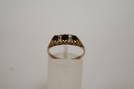 A three stone sapphire 9ct gold ring, the graduated oval cuts with pairs of diamonds between, to a