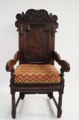 A 17th century and later oak armchair with a carved back panel