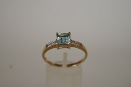 An aquamarine single stone 9ct gold ring, the square cut stone between diamond single cut shoulders,