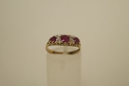 A ruby and diamond 9ct gold ring, the three graduated round cuts with pairs of single cut points