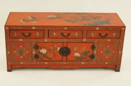 A Chinese red lacquered chest of drawers with typical scenes