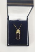 A smoky quartz, peridot and diamond 9ct gold pendant, the oval cut quartz with four graduated
