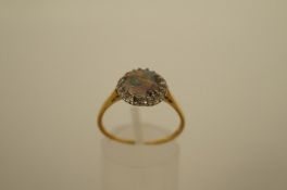 An opal and diamond cluster ring, the circular shallow cabochon enclosed by eighteen single cut