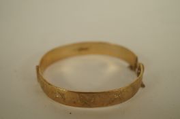 A 9ct gold solid hinged bangle, half engraved decoration, internal diameter 6cm, 32.9 grams gross