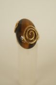 A 9ct gold Tiger's eye ring, the large cabochon held by two spiral motifs, finger size N, 10.3 grams