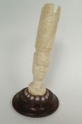 A carved ivory head of an African with pearls and large carved headress