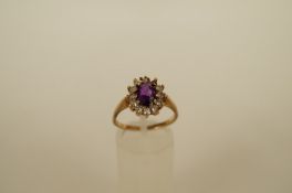A 9ct gold cluster ring, set with an oval cut amethyst enclosed by synthetic colourless stones,