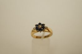 A sapphire and diamond 18ct gold cluster ring, the six round cut sapphires enclosing a central