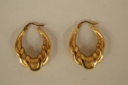 A pair of 9ct gold creole earrings the oval hoops decorated with polished loops against a matt