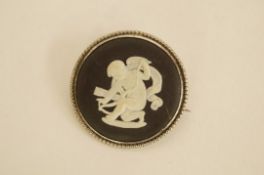 A Wedgwood ceramic brooch, circa 1965, depicting cupid; with a shell set pendant on a chain
