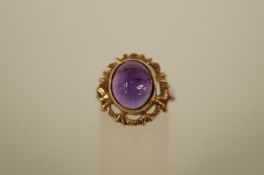 An amethyst 9ct gold dress ring, the oval cabochon set to a mount with an open work border, finger