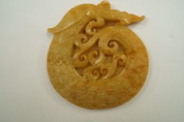 An oriental carved yellow jade dragon pendant
