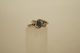 A three stone sapphire and diamond 9ct gold cross over ring the round cut stone flanked either