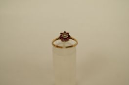 A 9ct gold ruby and diamond cluster ring, the central small brilliant cut enclosed by four round cut