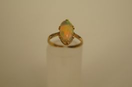 A single stone opal ring, the long oval cabochon, 11.8mm long, between shoulders with a rose cut