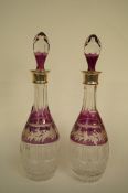 A pair of silver mounted glass decanters, the amethyst overlay with fruiting vine, the  silver