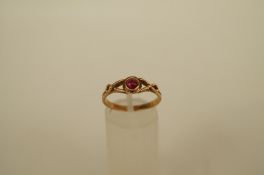 A single stone ruby ring, the small round cabochon between open wire work shoulders, finger size