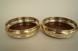 A pair of silver wine coasters, by Belo, Birmingham 1979, the plain rim to a turned wooden base,