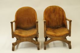 A pair of 20th century beech leather covered chairs with a lion emblem stamped in the back